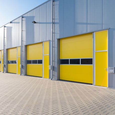 exterior of a commercial warehouse with yellow garage doors lansing mi